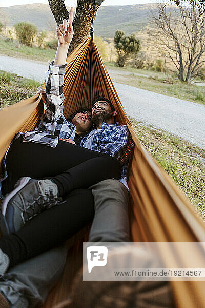Girlfriend and boyfriend spending leisure time lying down in hammock