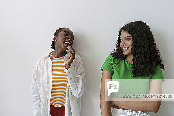 Young friends laughing in front of wall