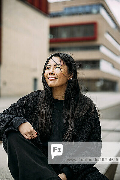 Smiling beautiful businesswoman sitting outside office building