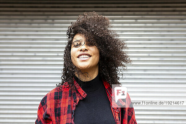 Smiling woman with curly hair in front of shutter