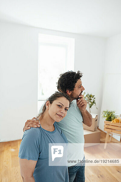 Smiling woman standing with thoughtful man at home