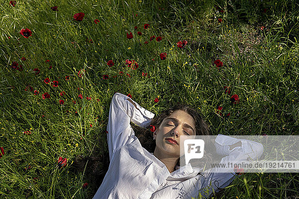 Woman relaxing on grass with poppy flowers