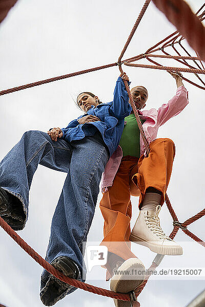 Couple standing on rope equipment in park