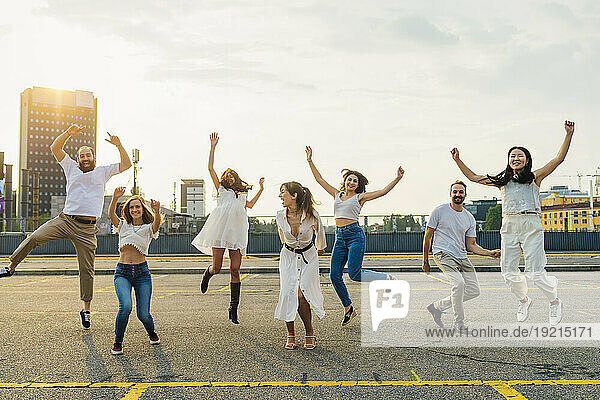 Cheerful friends jumping and together enjoying on road