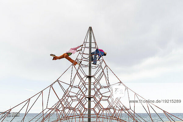 Playful couple having fun on rope equipment under sky