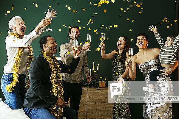 Cheerful family with drinking glasses enjoying new year party at home