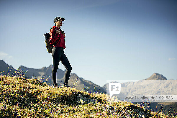 Young woman with backpack hiking at mountains on sunny day