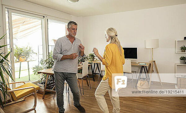 Carefree couple dancing together in living room at home