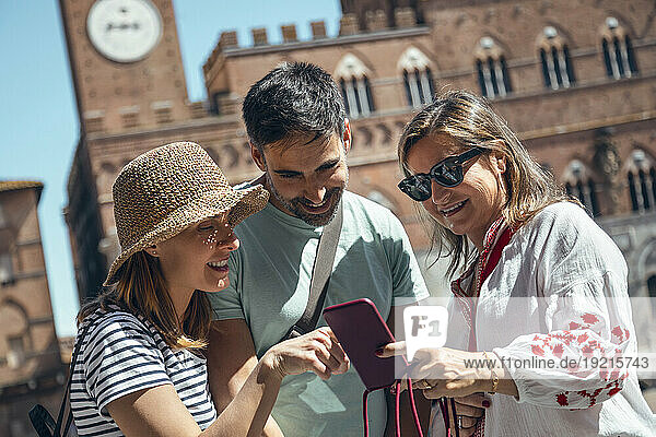 Happy tourists sharing smart phone on sunny day