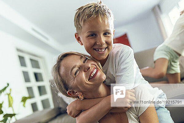 Smiling boy hugging mother in living room