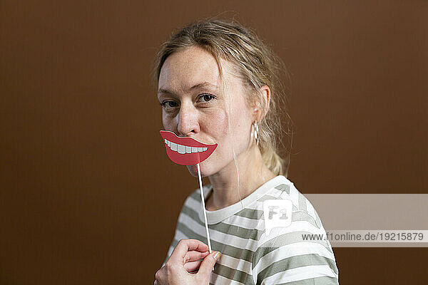 Blond woman holding lip prop in studio