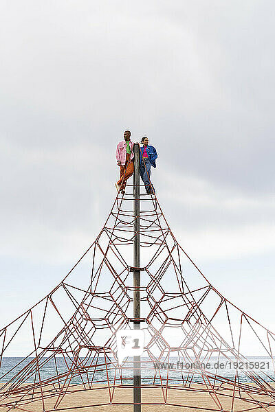 Contemplative couple standing on rope equipment in park