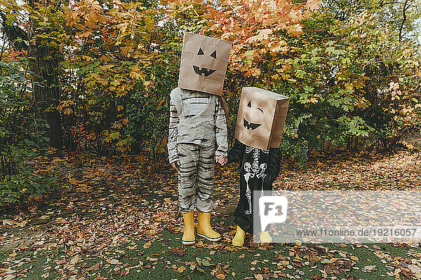 Playful friends in costumes holding hands in garden