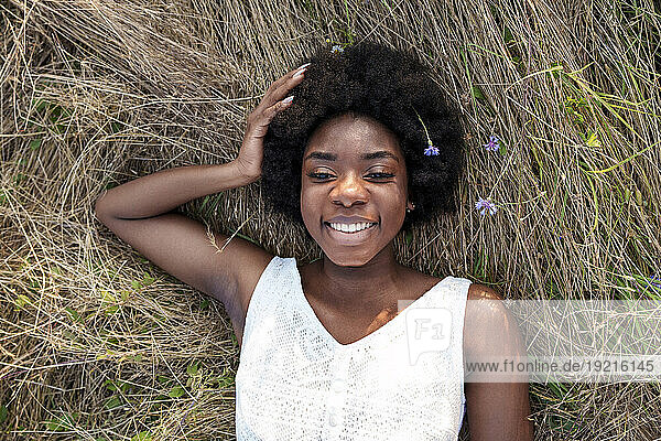 Happy young woman relaxing on dry grass
