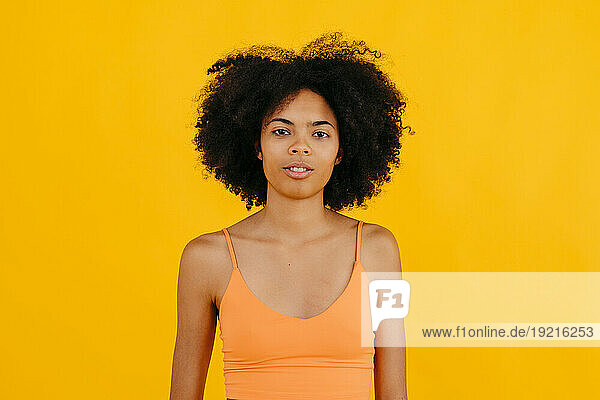 Young woman with curly hair against yellow background