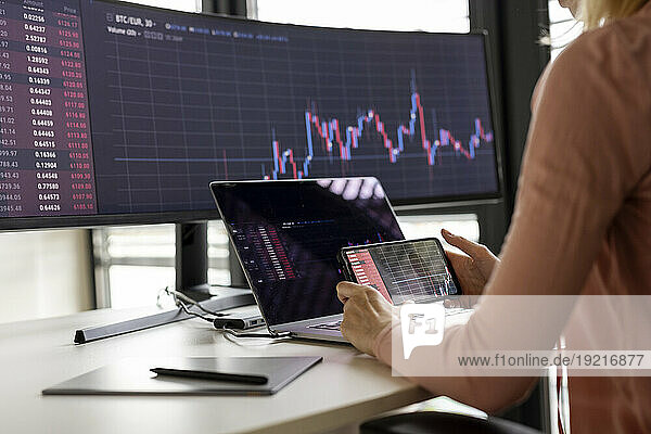 Businesswoman examining graph on smart phone at desk