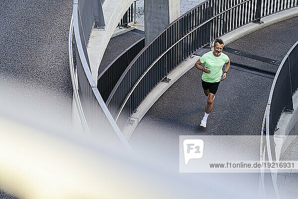 Mature athlete running on footbridge