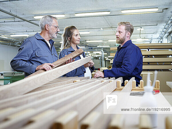 Carpenters discussing over wooden plank in industry