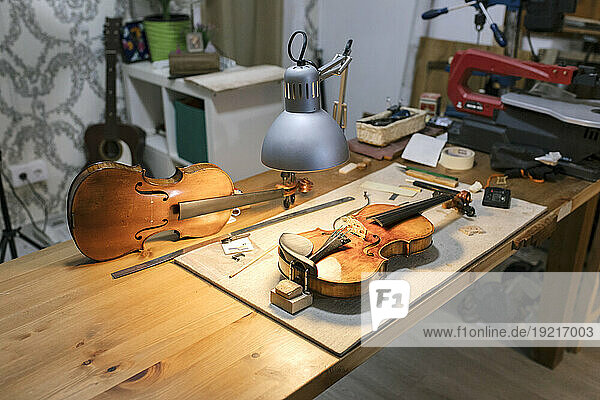 Unfinished violins kept under desk lamp in workshop