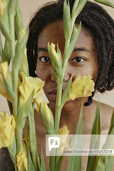 Woman with bunch of yellow gladiolus flowers against brown background