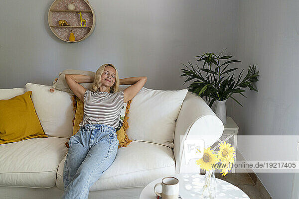 Mature woman relaxing on sofa in living room at home
