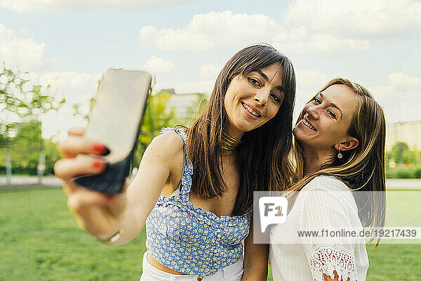 Happy woman taking selfie with friend in park