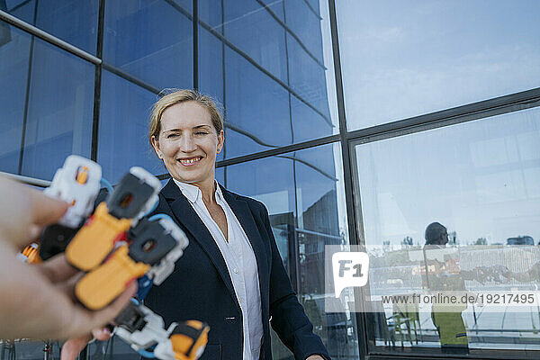 Smiling female architect examining robotic arm near office building