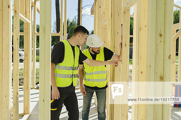 Engineers examining wooden frame and discussing at construction site