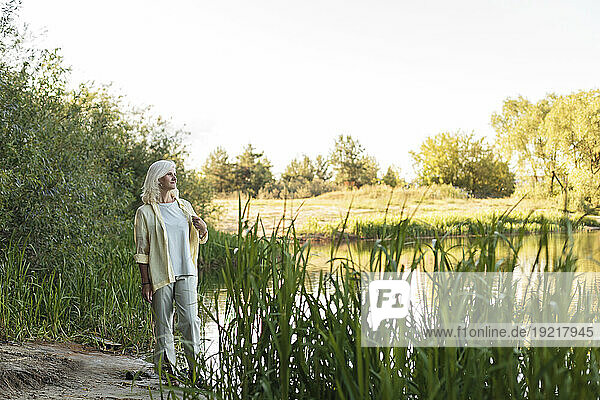 Mature woman walking by plants at lakeshore