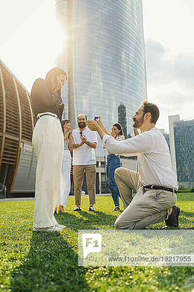 Happy man proposing woman with ring on sunny day
