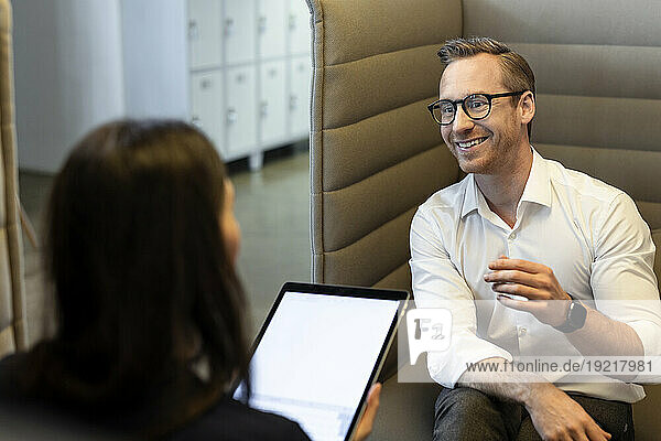 Happy businessman discussing with colleague in office