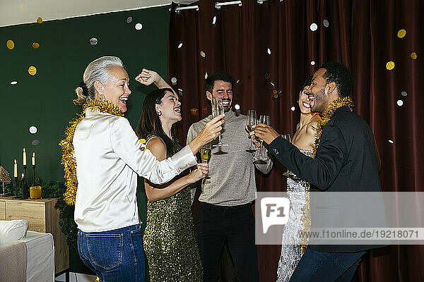 Happy men and women with drinking glasses dancing at new year party