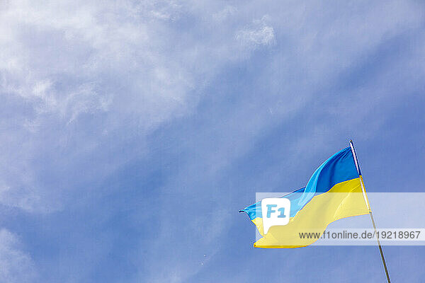 Ukrainian flag in a blue sky with some clouds