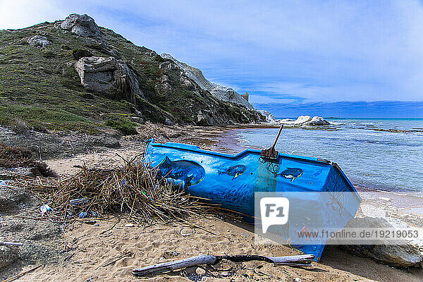 Europe  Italy  Sicily  abandoned migrant boat painted blue on a beach