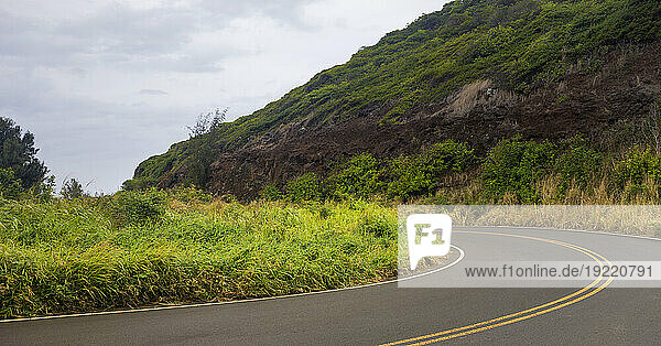 Close-up of a curve in the road and cloudy sky through the green hills along a scenic drive in West Maui; Maui  Hawaii  United States of America