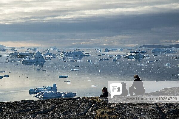 Rodebay  Grönland  Juli 09  2018: Eine Gruppe von Menschen sitzt und schaut sich Eisberge an. Rodebay  auch bekannt als Oqaatsut  ist eine Fischersiedlung nördlich von Ilulissat  Nordamerika