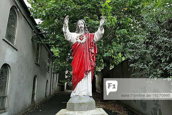 Eine rote religiöse Statue von Jesus mit ausgestreckten Armen in einer Gasse in der Stadt Waterford. Waterford  Irland  Europa