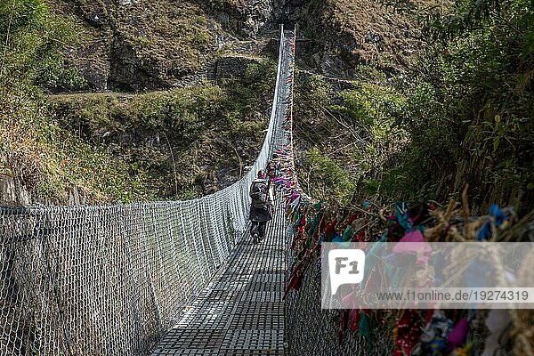 Annapurnaregion Nepal  11. November 2014: Menschen überqueren eine Hängebrücke über einen Fluss in der Annapurnaregion