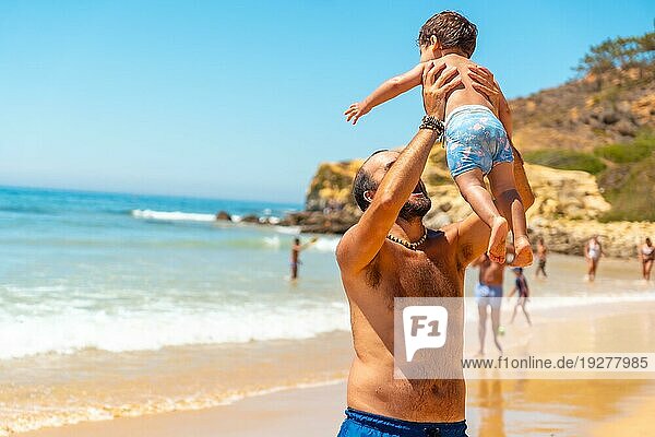 Vater spielt im Sand und hat Spaß mit seinem Sohn  Strand Praia do Barranco das Belharucas  Albufeira  Algarve. Portugal