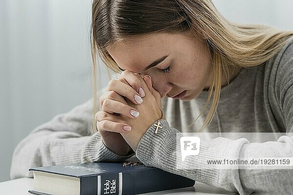 Junge Frau betet mit Kreuz Halskette Bibel halten