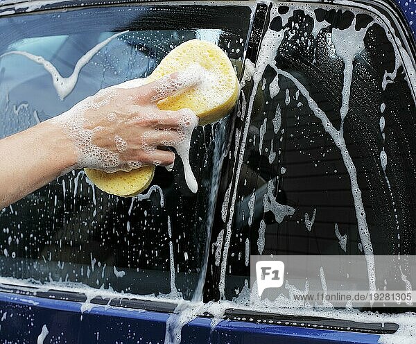 Mann wäscht ein Auto mit einem gelben Schwamm