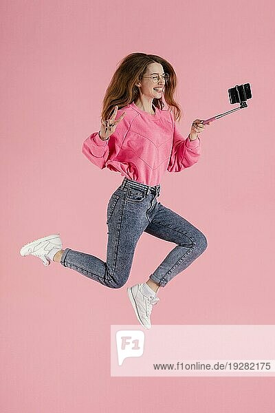 Porträt glückliche Frau springt mit Selfie Stick