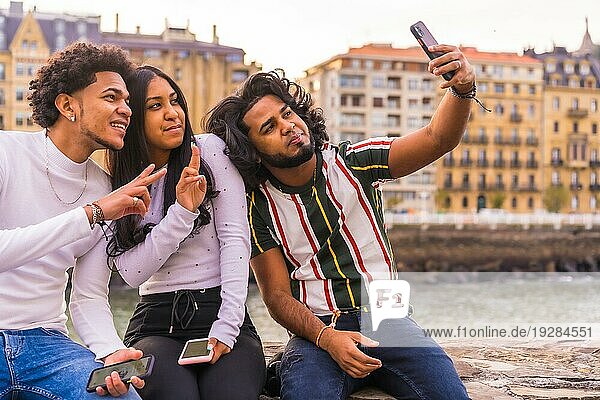Lifestyle  drei schwarze Freunde  die Spaß haben und ein Selfie machen. Afrohaar Junge  Brünette Junge mit langen Haaren und Brünette Mädchen