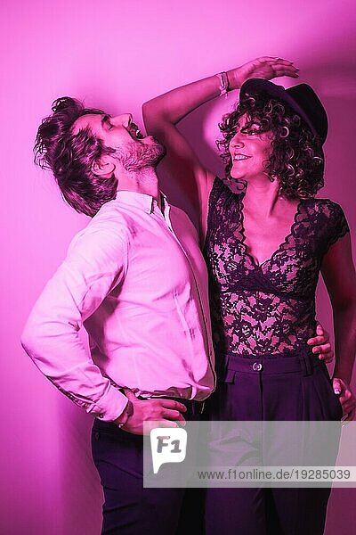 Studio Lifestyle  ein junges  verliebtes Paar  das sich am Valentinstag amüsiert  beleuchtet von einem rosa Neonlicht