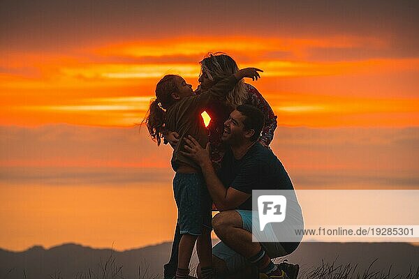 Eine Familie  die sich auf dem Gipfel eines Berges bei Sonnenuntergang umarmt und Spaß hat. Abenteuer Lebensstil Ein Sommernachmittag in den Bergen des Baskenlandes