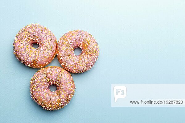 Rosa Donuts und Süßigkeiten auf blauem Hintergrund  Copy Space Flat Lay