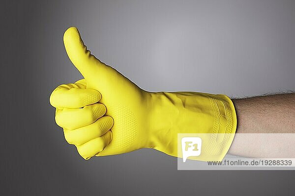 Eine Hand mit gelbem Schutzhandschuh macht ein Daumen hoch Zeichen