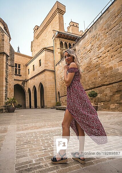 Porträt einer blonden Frau in einer mittelalterlichen Burg  die ein rotes Kleid trägt und sich amüsiert