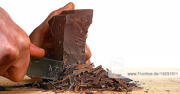 Mann schneidet schwarze Schokolade mit Messer