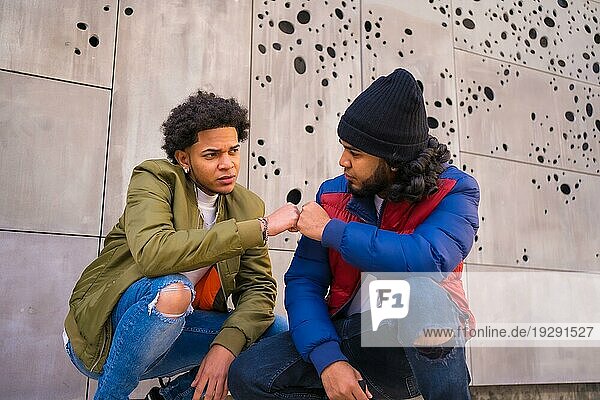 Urbaner Stil  Porträt von zwei schwarzen Latino Freunden  die Spaß auf der Straße haben. Afro Haar Junge  Brünette Junge mit langen Haaren mit Hut